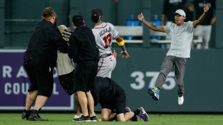 A fan charges at Atlanta Braves right fielder Ronald Acuna Jr. as security detains another person in the seventh inning against the Colorado Rockies at Coors Field.