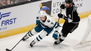 Nico Strum #7 of the San Jose Sharks skates the puck around the net past Andreas England #5 of the Los Angeles Kings during the first period of their pre-season game