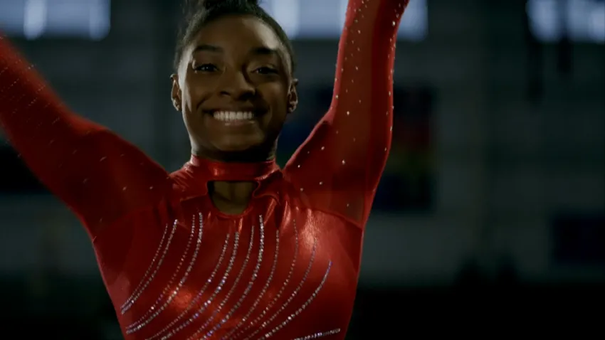 Simone Biles raises her arms after competing