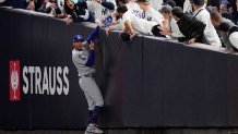 Fans interfere with a foul ball caught by Los Angeles Dodgers right fielder Mookie Betts during the first inning in Game 4 of the baseball World Series against the New York Yankees, Tuesday, Oct. 29, 2024, in New York. (AP Photo/Ashley Landis)