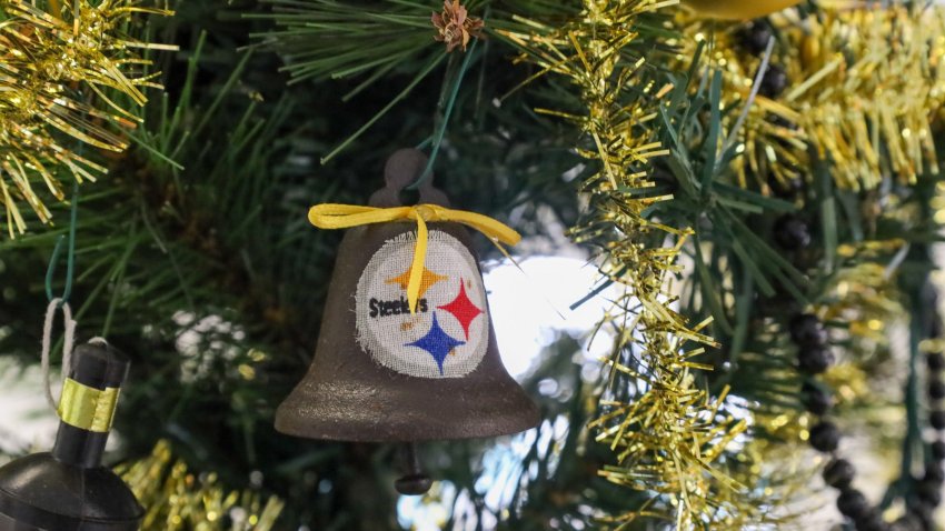 A bell adorned with the Pittsburgh Steelers logo and a yellow ribbon hangs from a Christmas tree