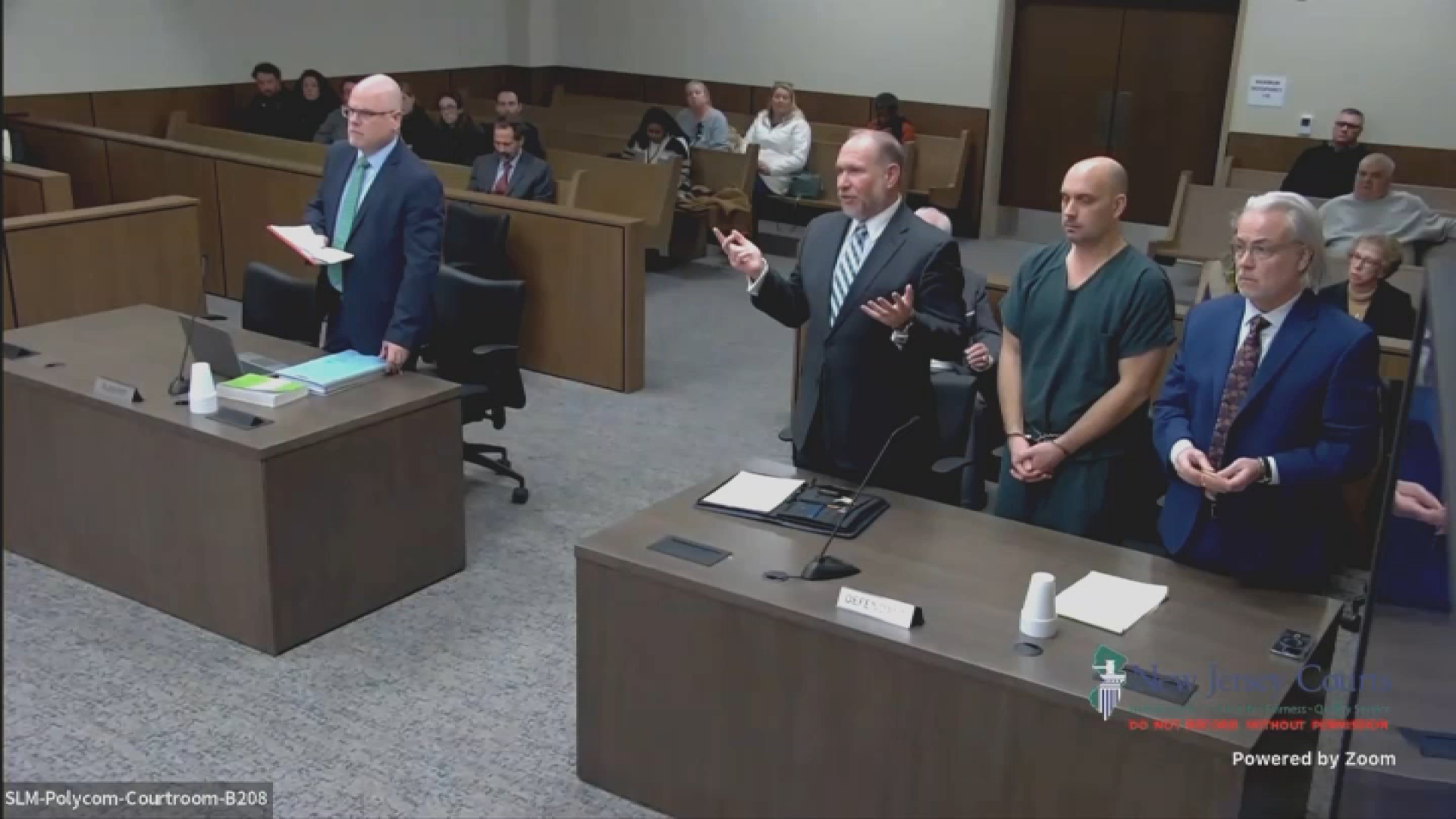 Sean Higgins, dressed in green, is flanked by his attorneys during a court appearance on Tuesday, Feb. 4, 2025.