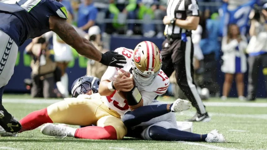 Sep 7, 2025; Seattle, Washington, USA; San Francisco 49ers quarterback Brock Purdy (13) is tackled during the first half against the Seattle Seahawks at Lumen Field. Mandatory Credit: Joe Nicholson-Imagn Images
